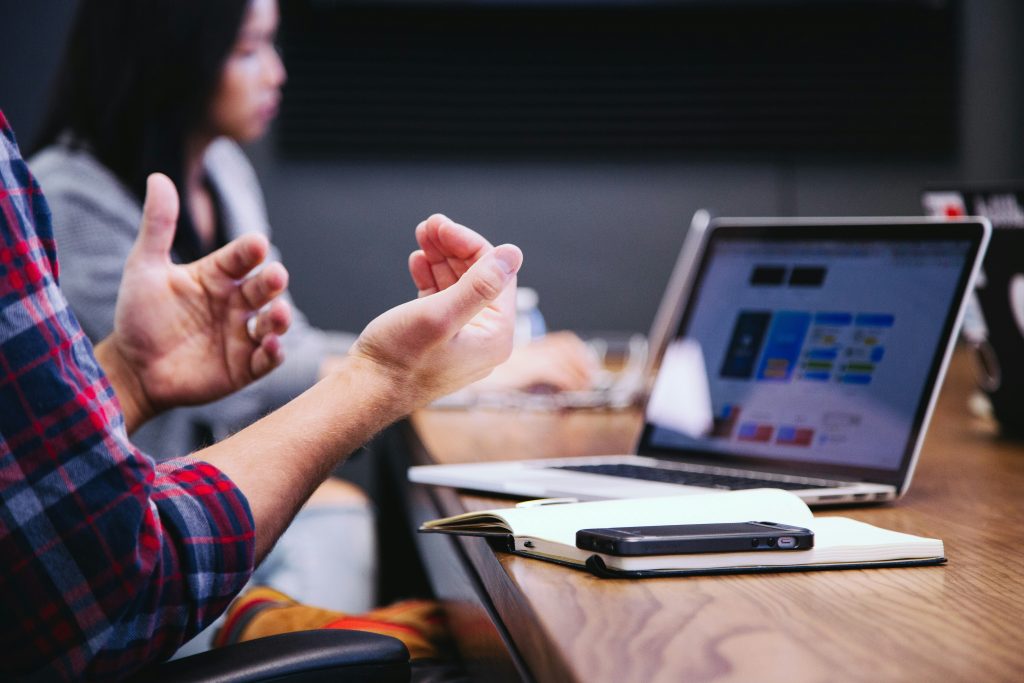 a person sitting at a table with their hands raised discussing a brand build