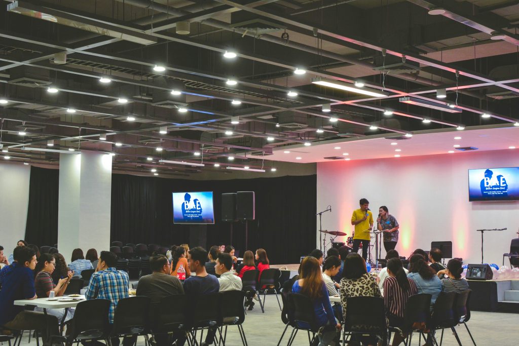 a group of people sitting in chairs and a stage with a microphone similar to networking events in Los Angeles.