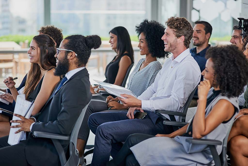 Smiling, engaged employees attend a small business seminar